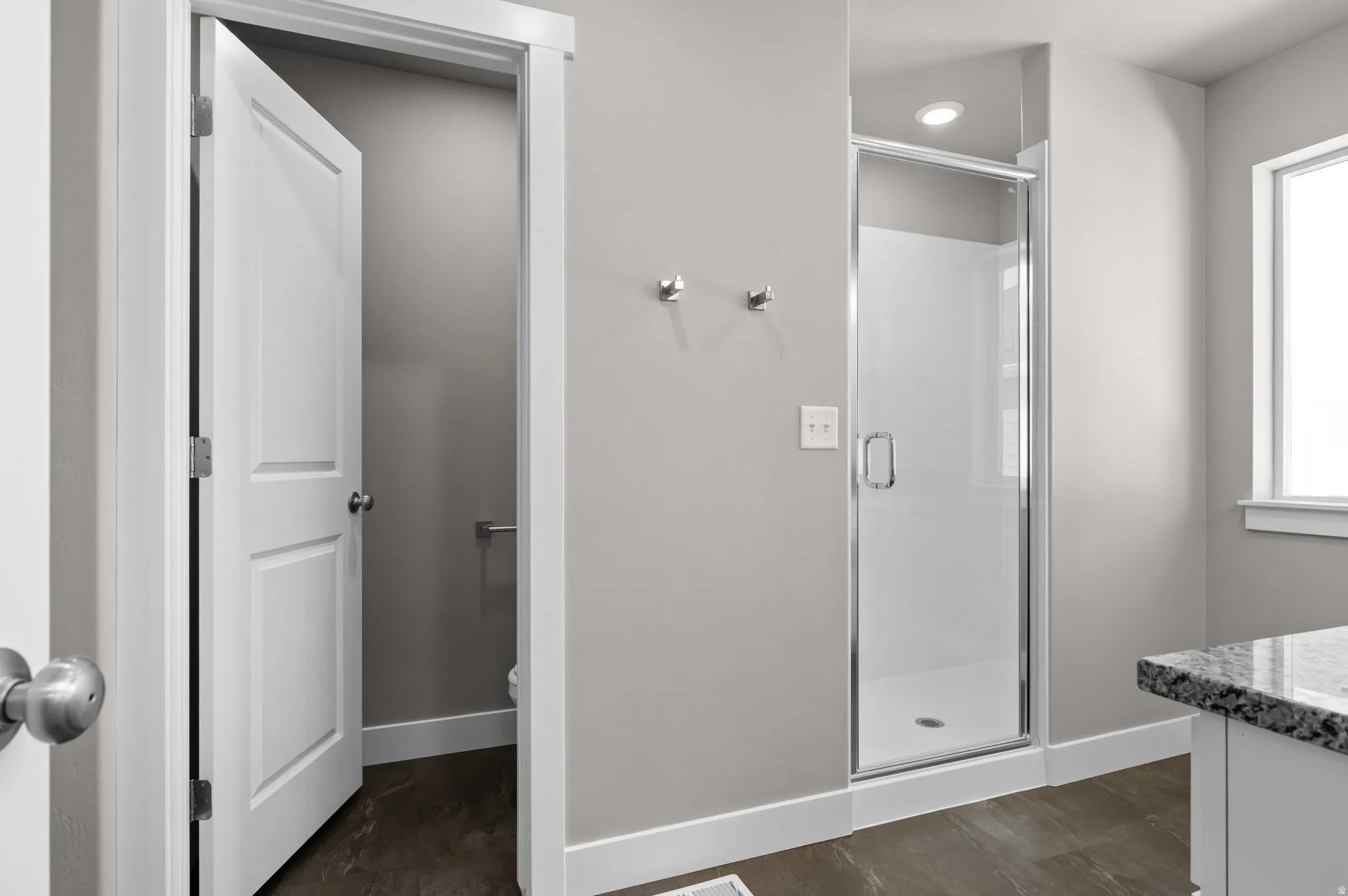 Shower enclosure with clear glass door, recessed lighting, and a window with white trim