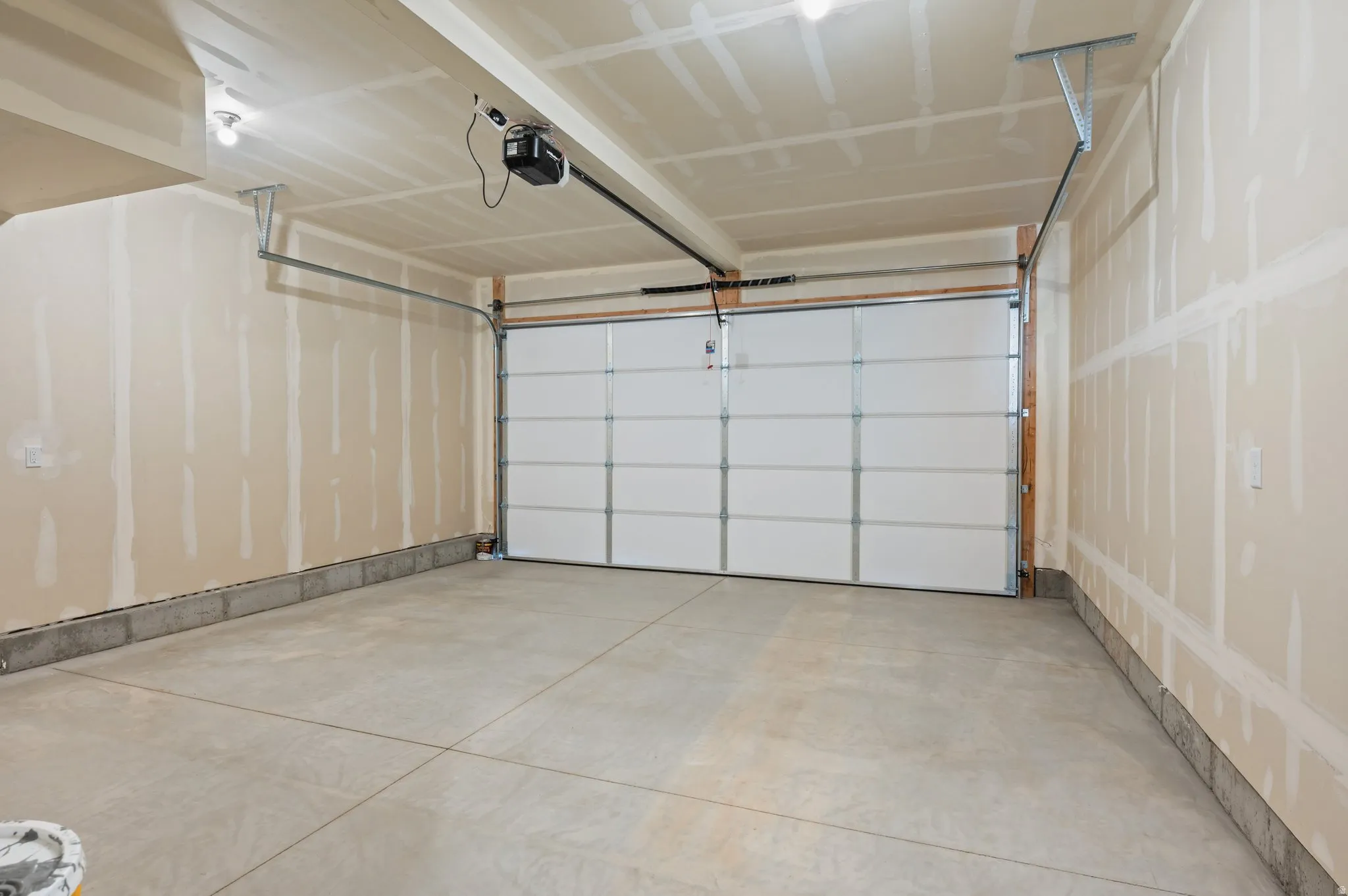 Spacious garage featuring a concrete floor, high ceilings, and a paneled garage door