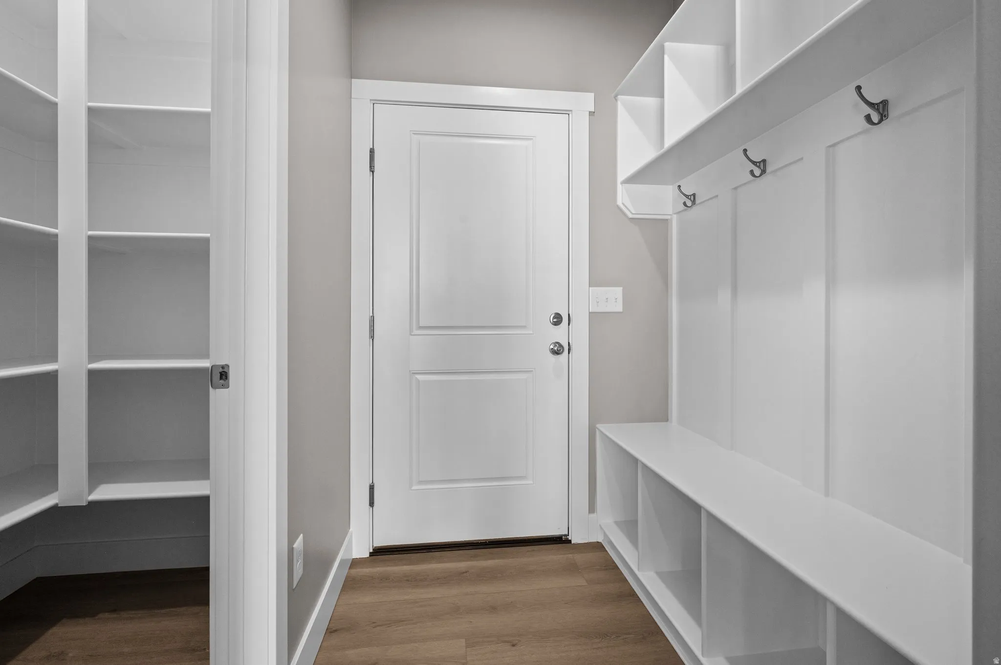 Mudroom entry featuring wood-finish flooring and a built-in storage bench with shelving and coat hooks