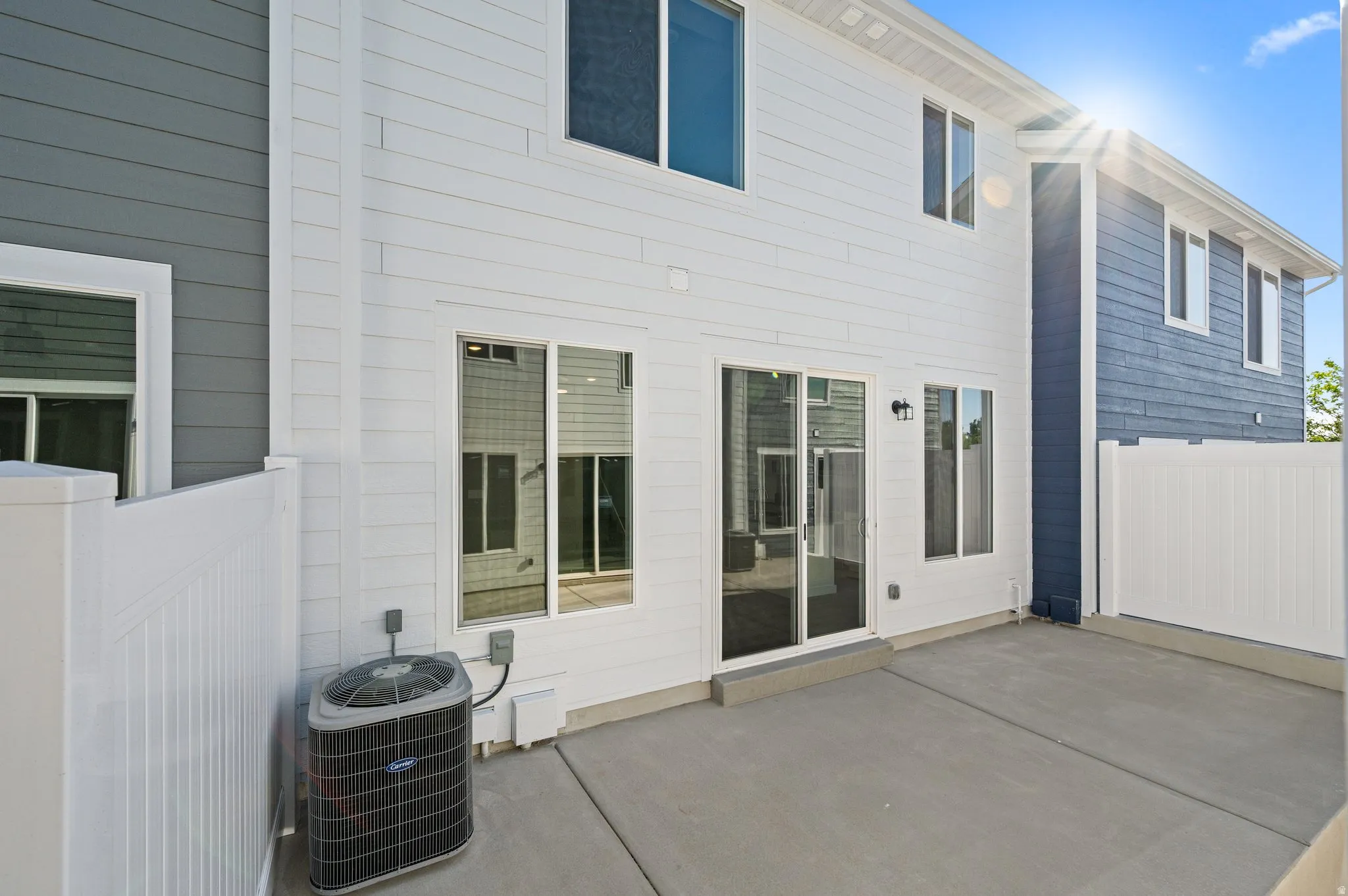 Private outdoor patio space featuring a concrete pad and white vinyl fencing