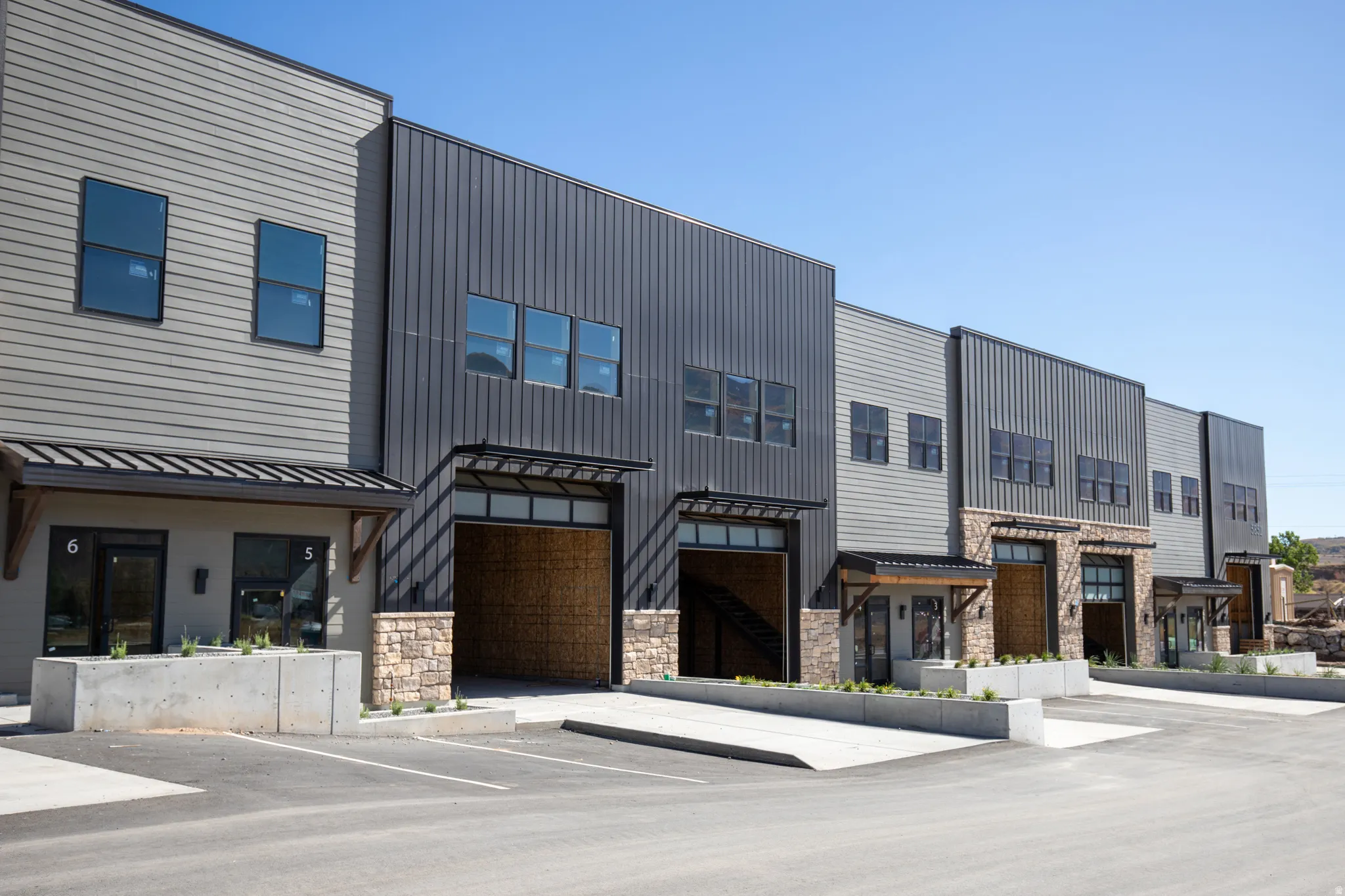 View of front facade featuring a standing seam roof, uncovered parking, and stone siding