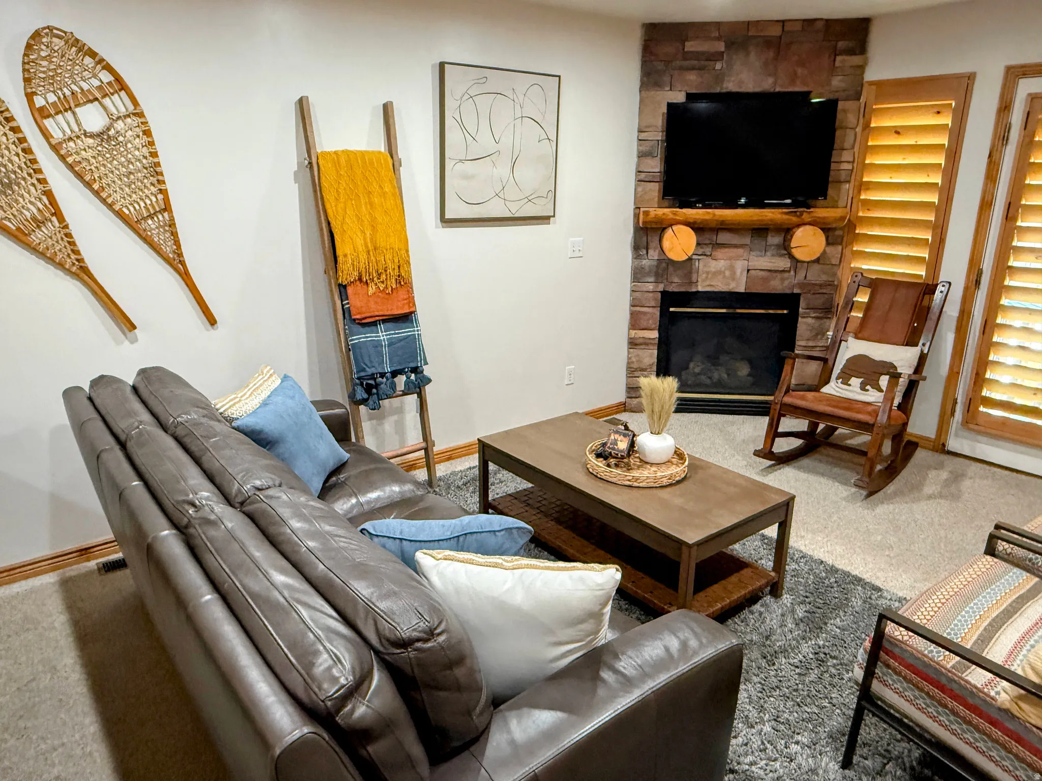 Living area with carpet flooring and a stone fireplace