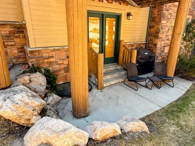 Entrance to property featuring stone siding and a patio