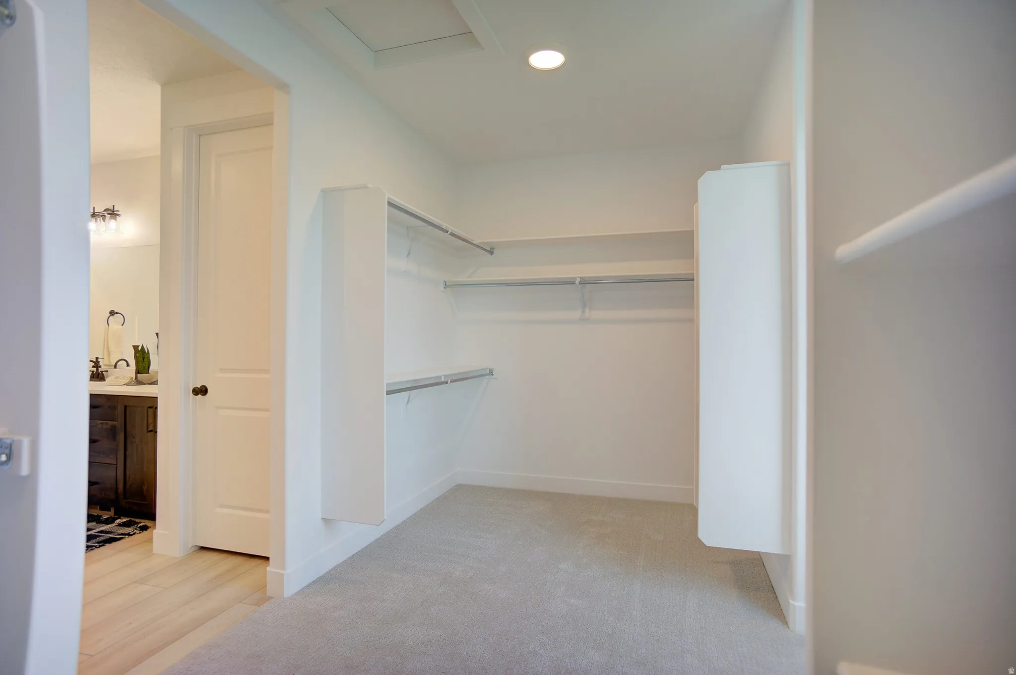 Walk in closet featuring attic access and light colored carpet
