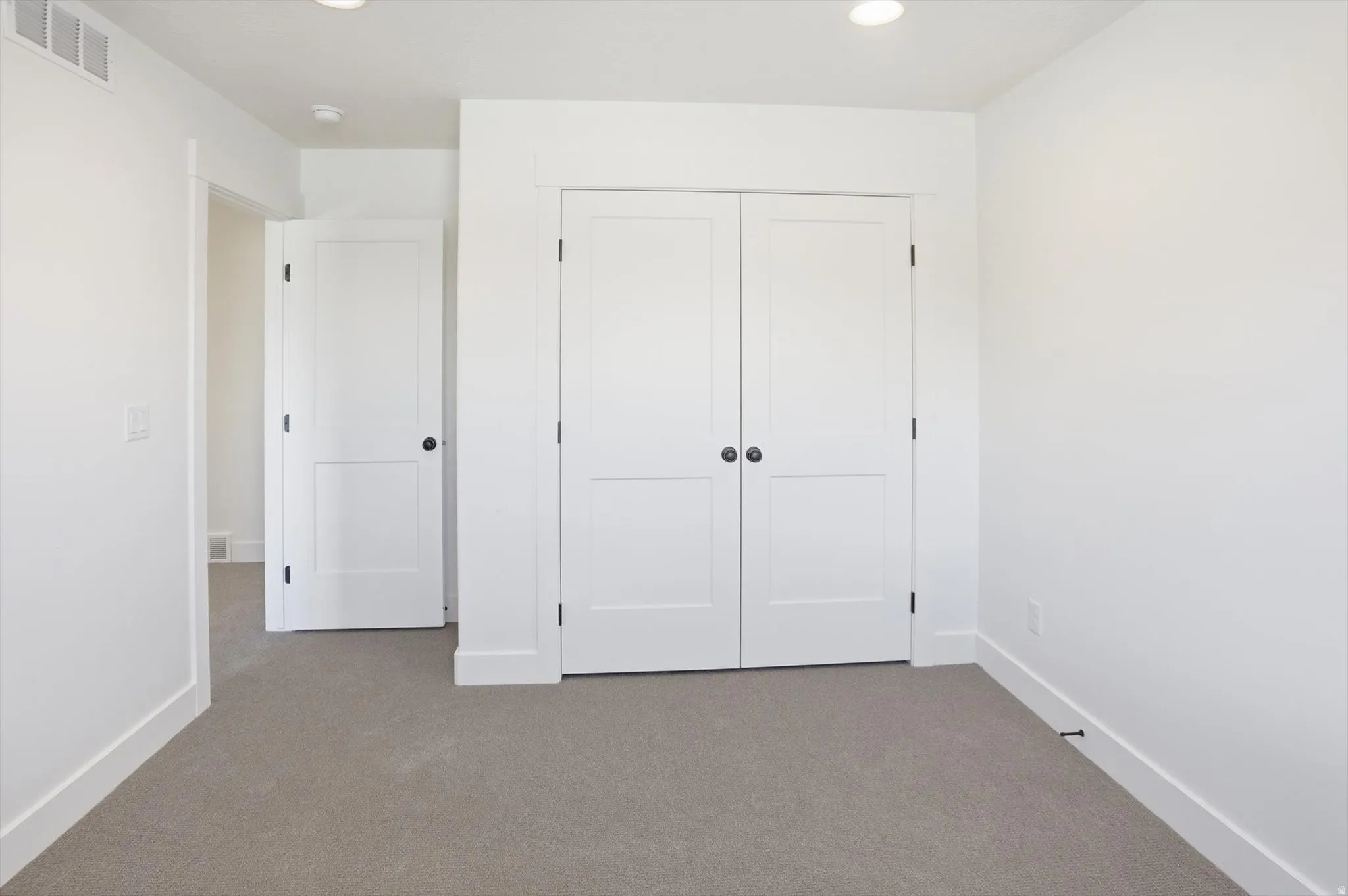 Unfurnished bedroom with carpet flooring, a closet, and recessed lighting
