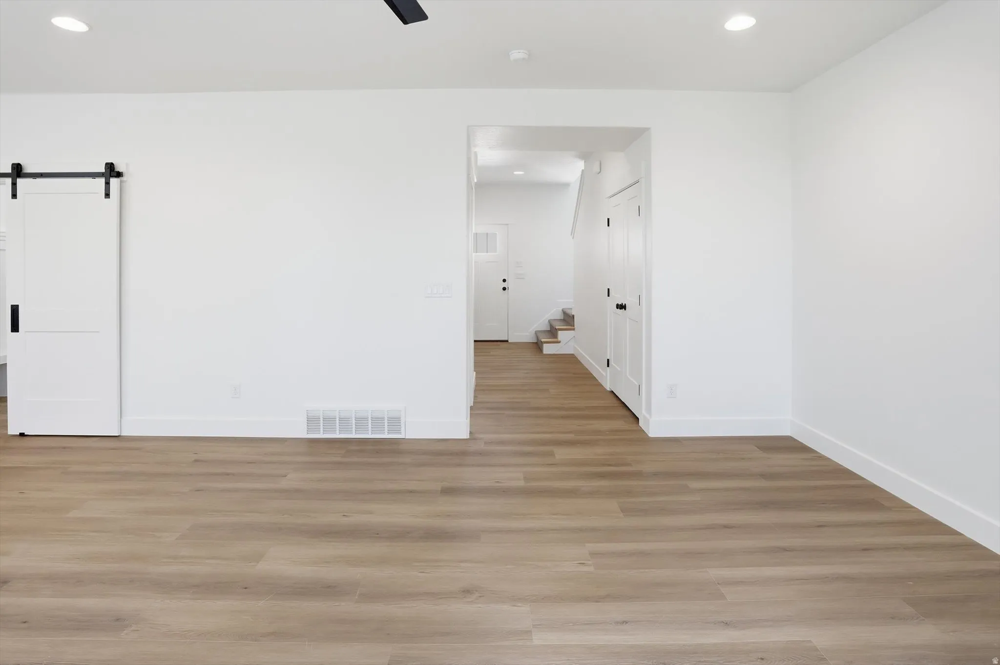 Unfurnished room with a barn door, recessed lighting, light wood finished floors, and a ceiling fan