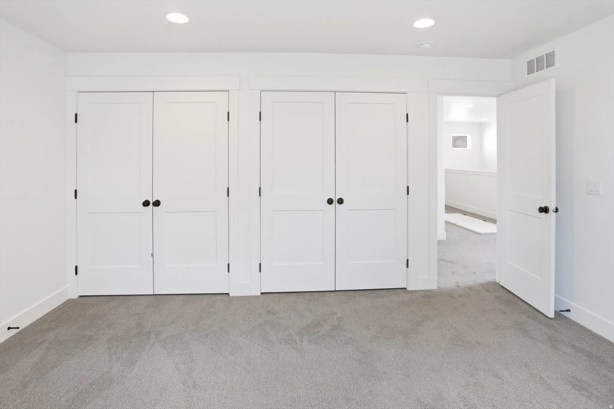 Unfurnished bedroom with two closets, light colored carpet, and recessed lighting