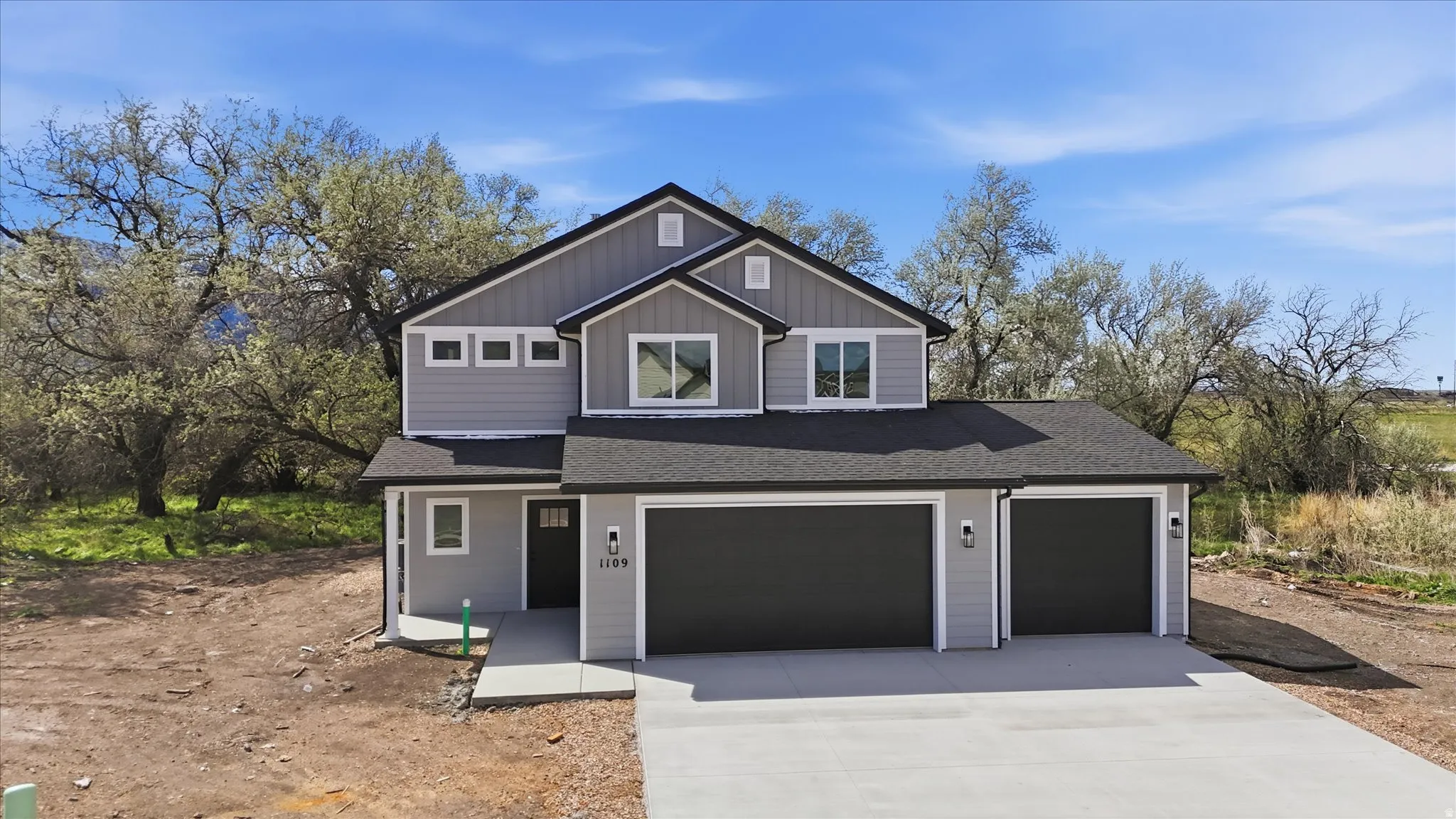 View of front of house featuring concrete driveway, roof with shingles, a garage, and board and batten siding