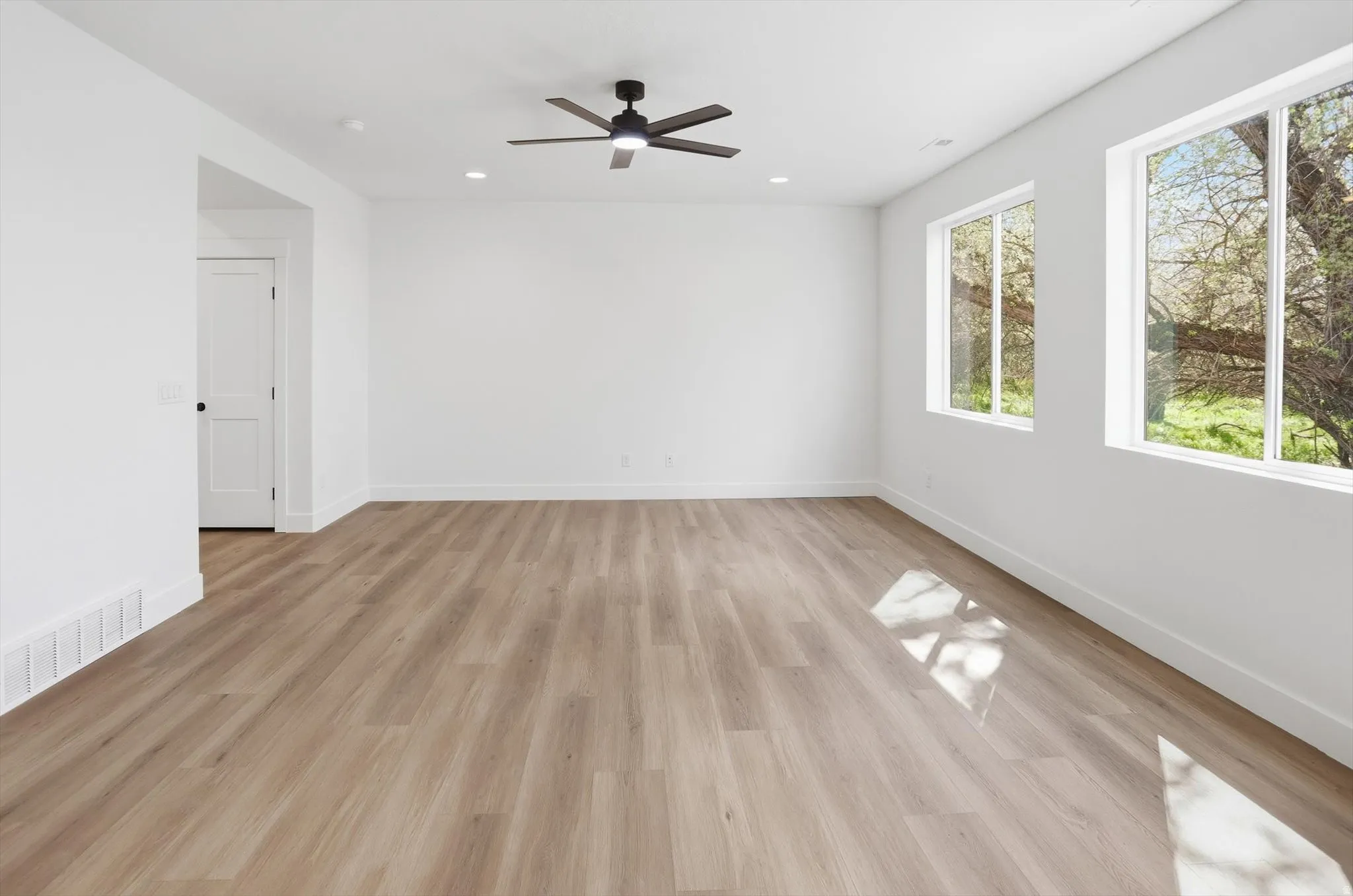 Empty room featuring light wood-style floors, a ceiling fan, and recessed lighting