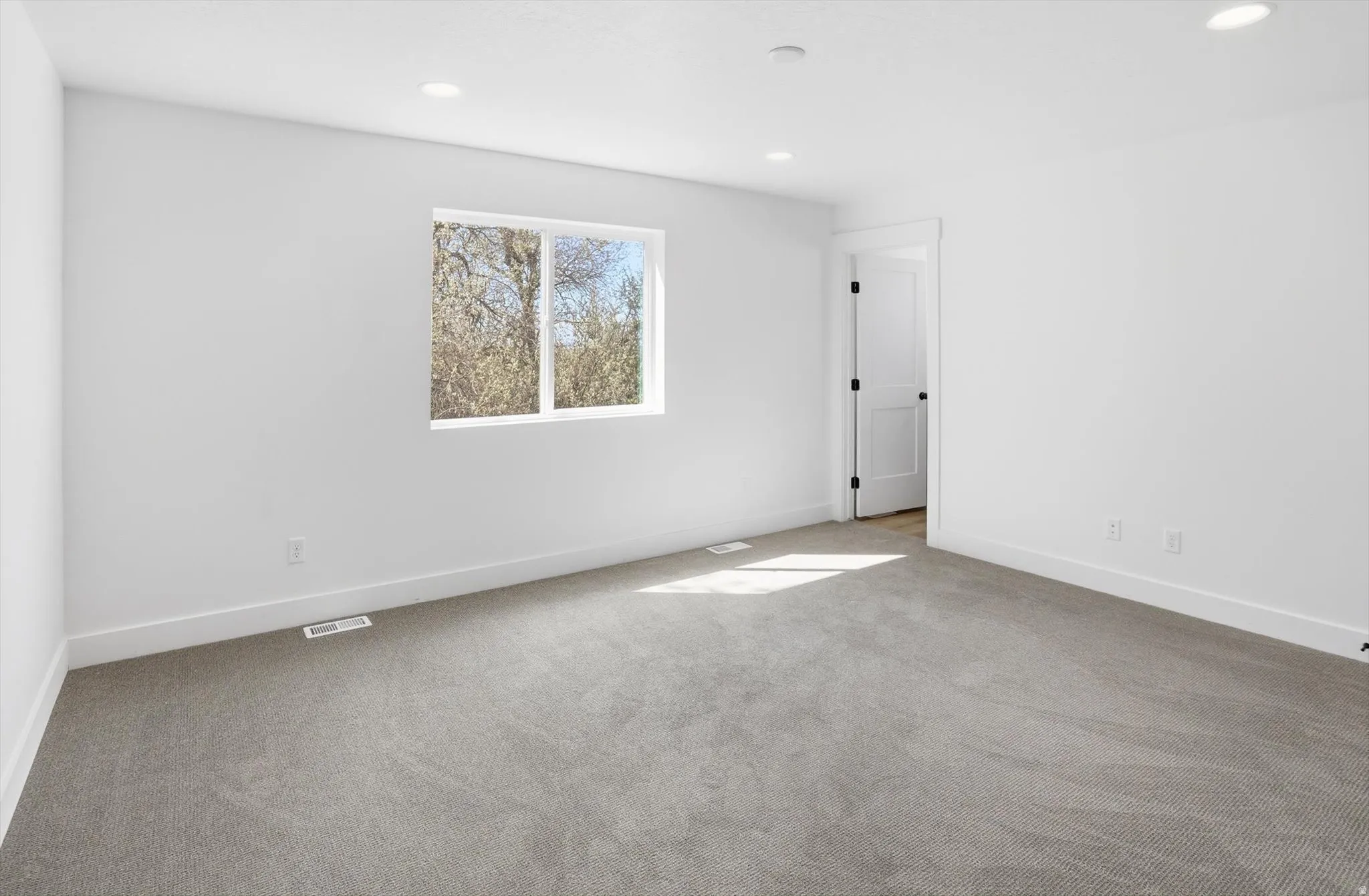 Empty room featuring light colored carpet and recessed lighting