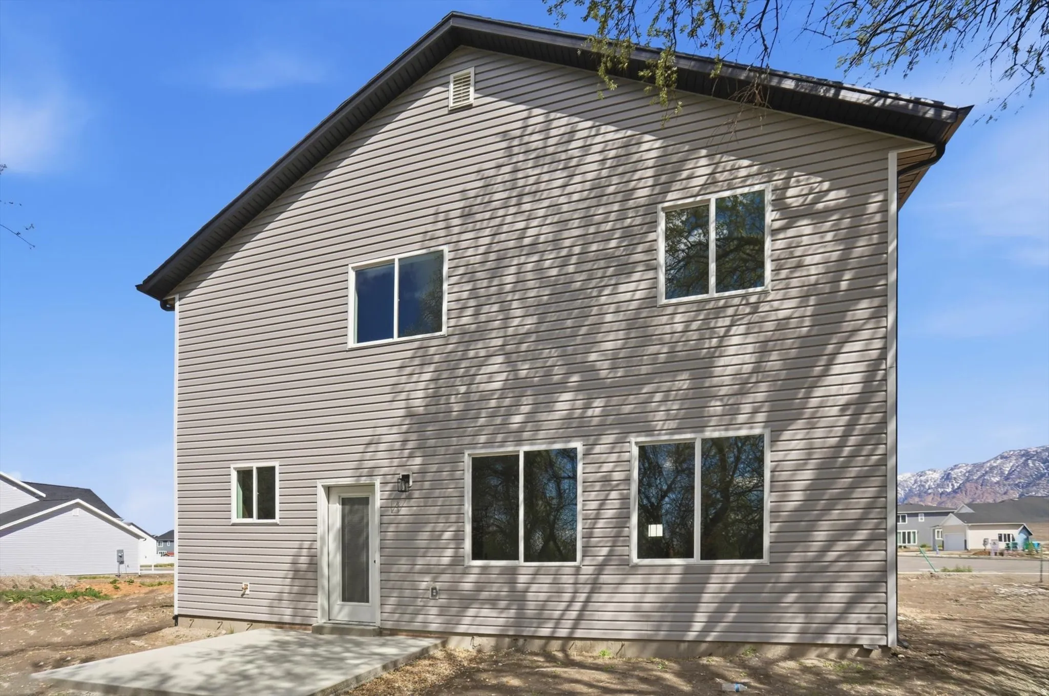 Back of house with a mountain view and a patio area