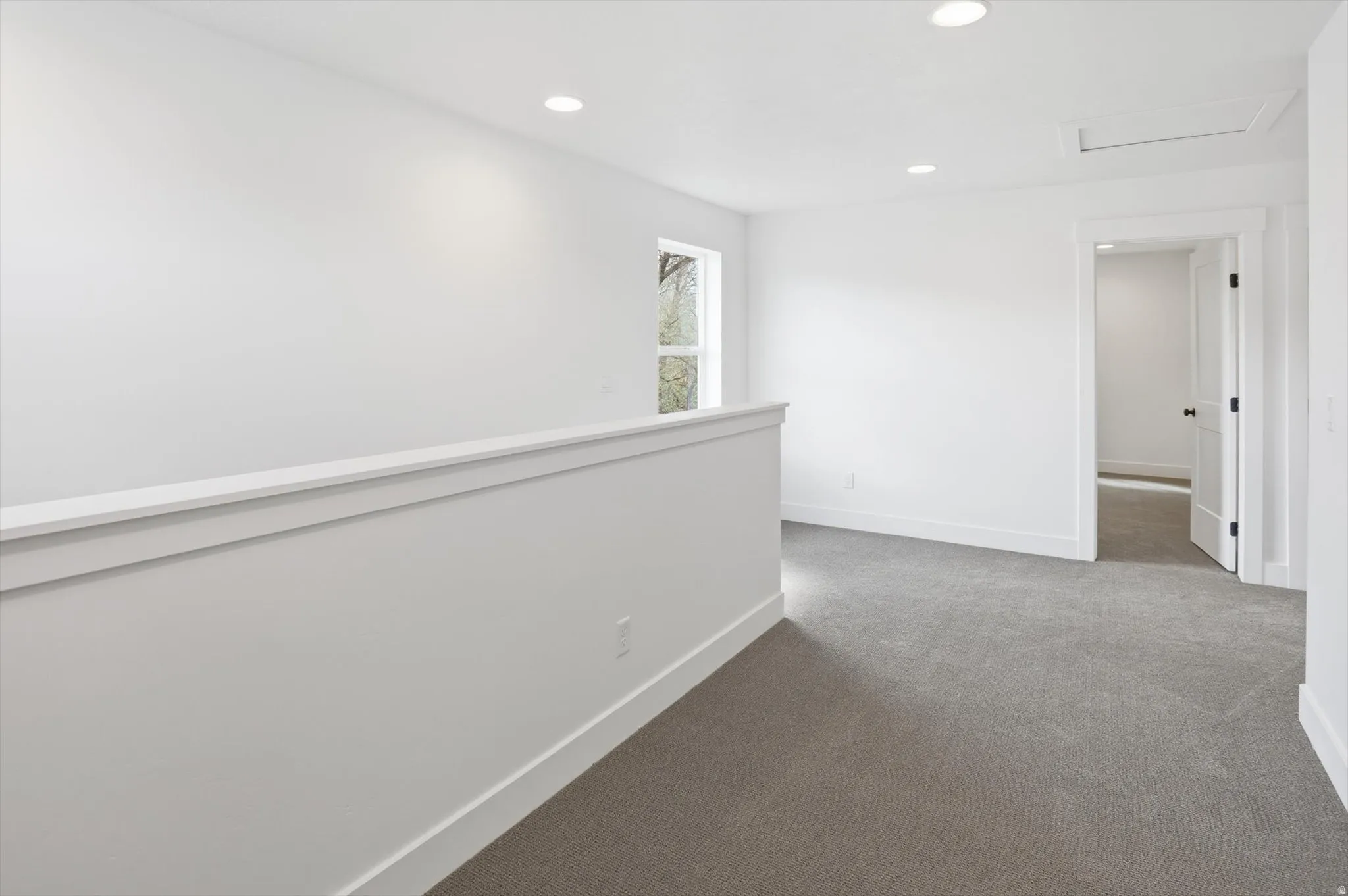 Hallway with dark colored carpet and recessed lighting