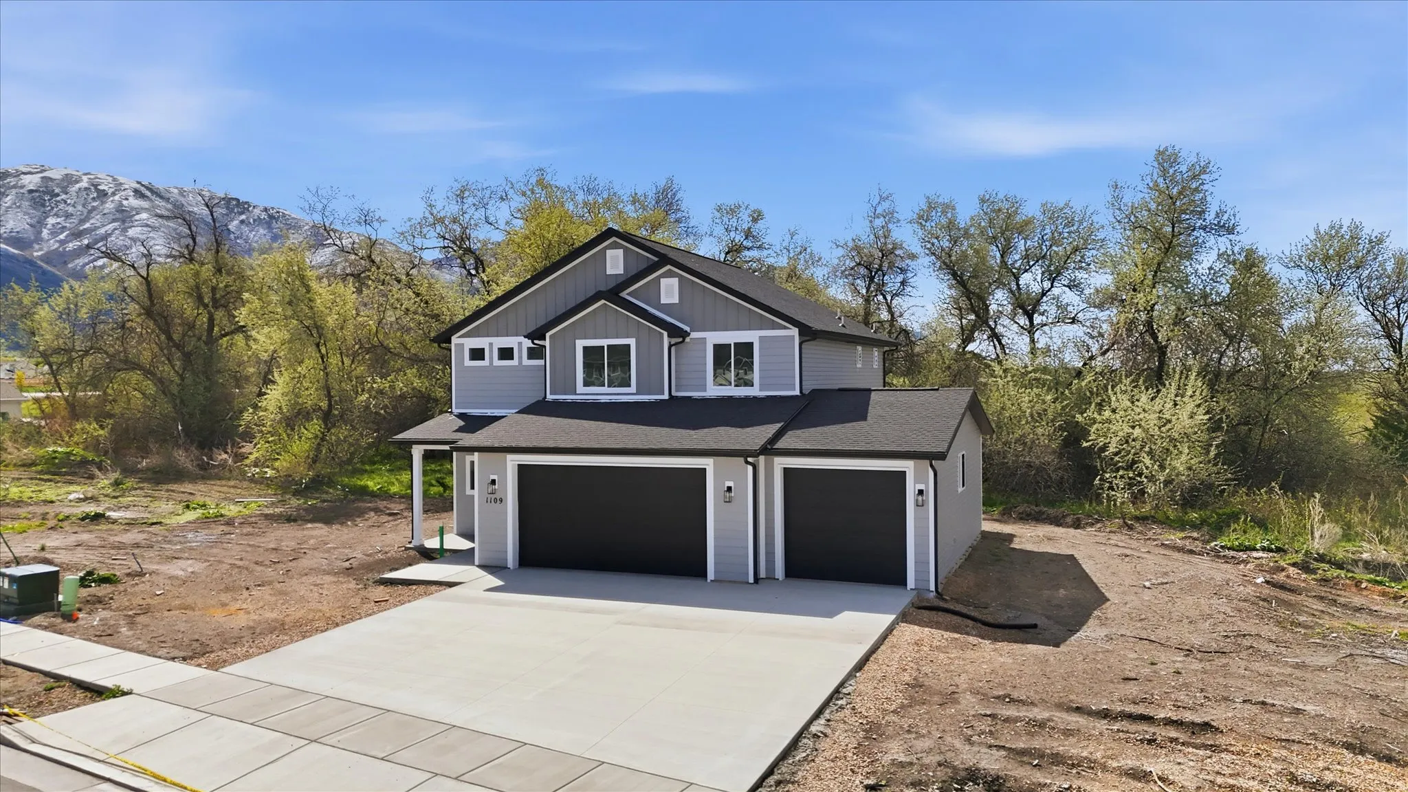 View of front facade with concrete driveway, a garage, roof with shingles, a mountain view, and board and batten siding