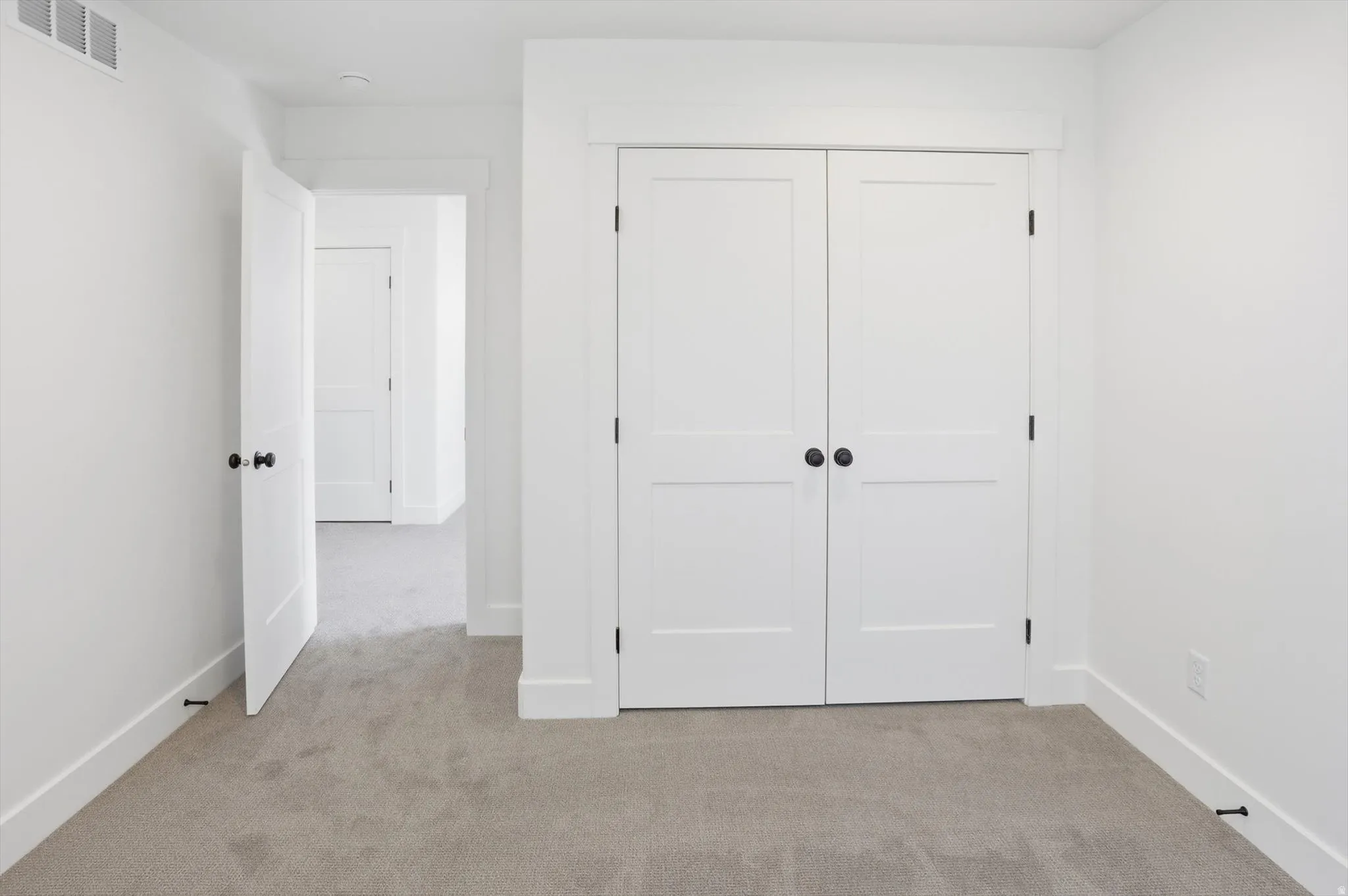 Unfurnished bedroom featuring light carpet and a closet