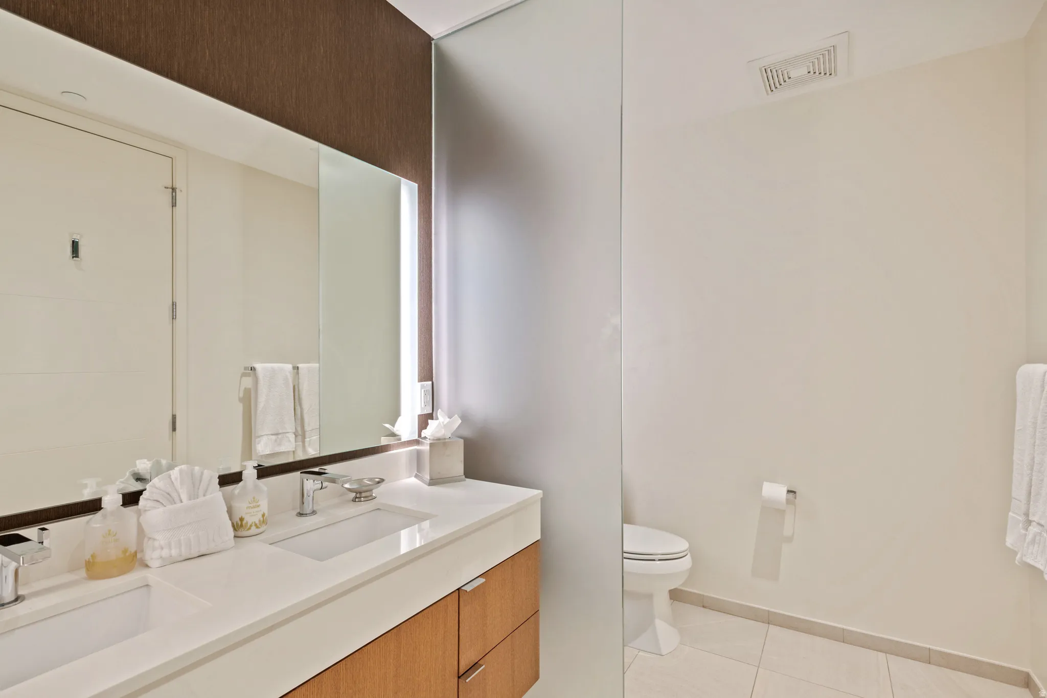 Bathroom with double vanity and light tile patterned floors
