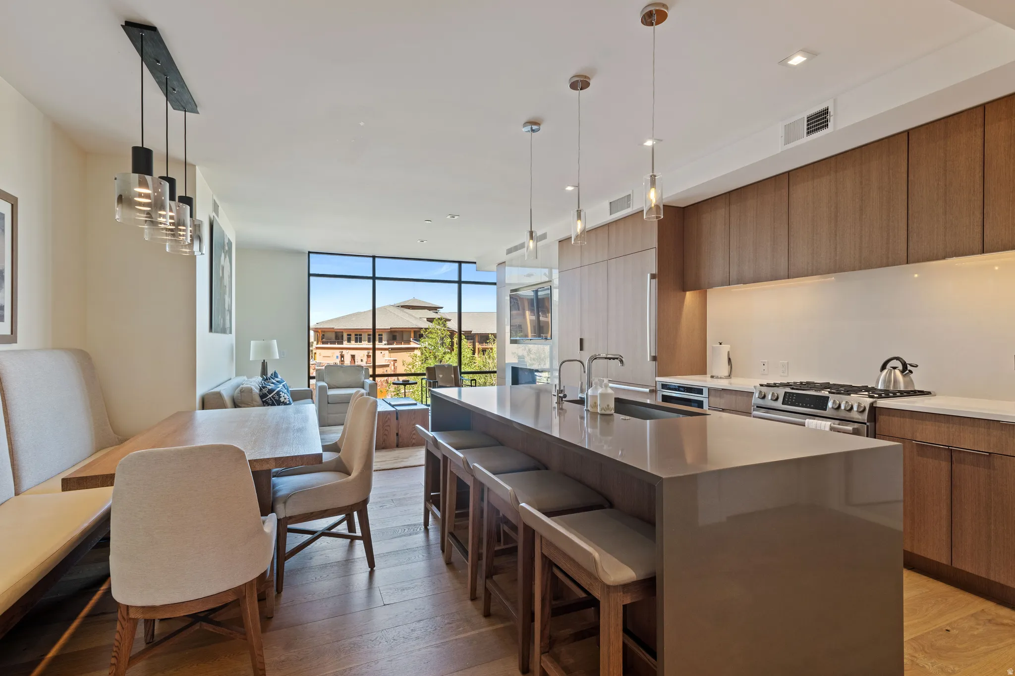 Dual tone kitchen featuring modern cabinets, open floor plan, a kitchen bar, light wood-style flooring, and dark stone countertops