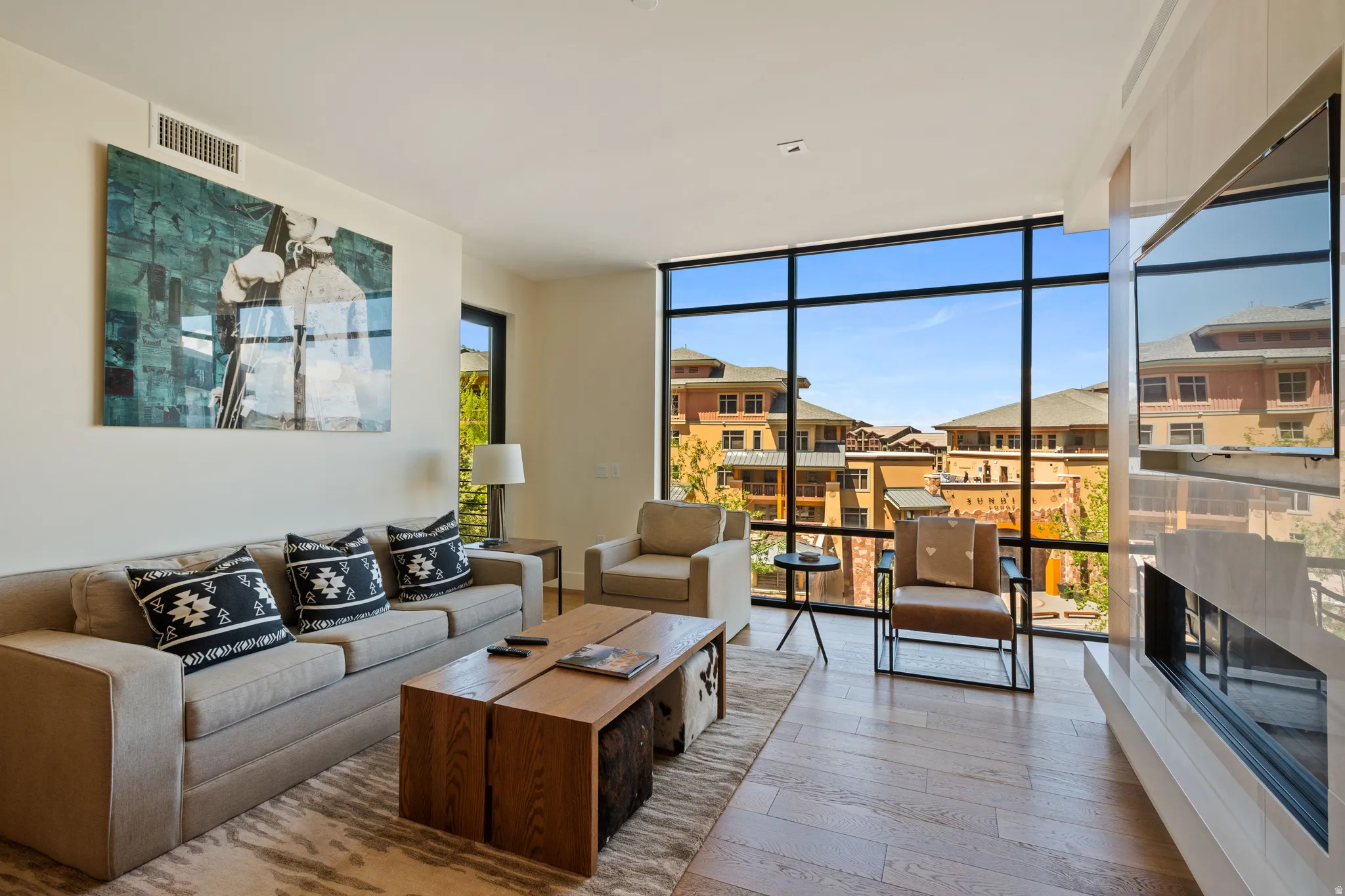 Living room featuring a fireplace, light wood finished floors, floor to ceiling windows, and a residential view