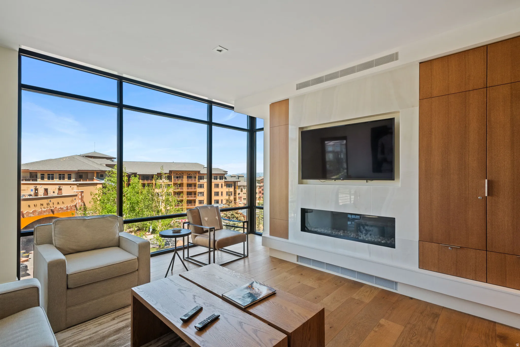Living area featuring floor to ceiling windows, a glass covered fireplace, and light wood-style floors