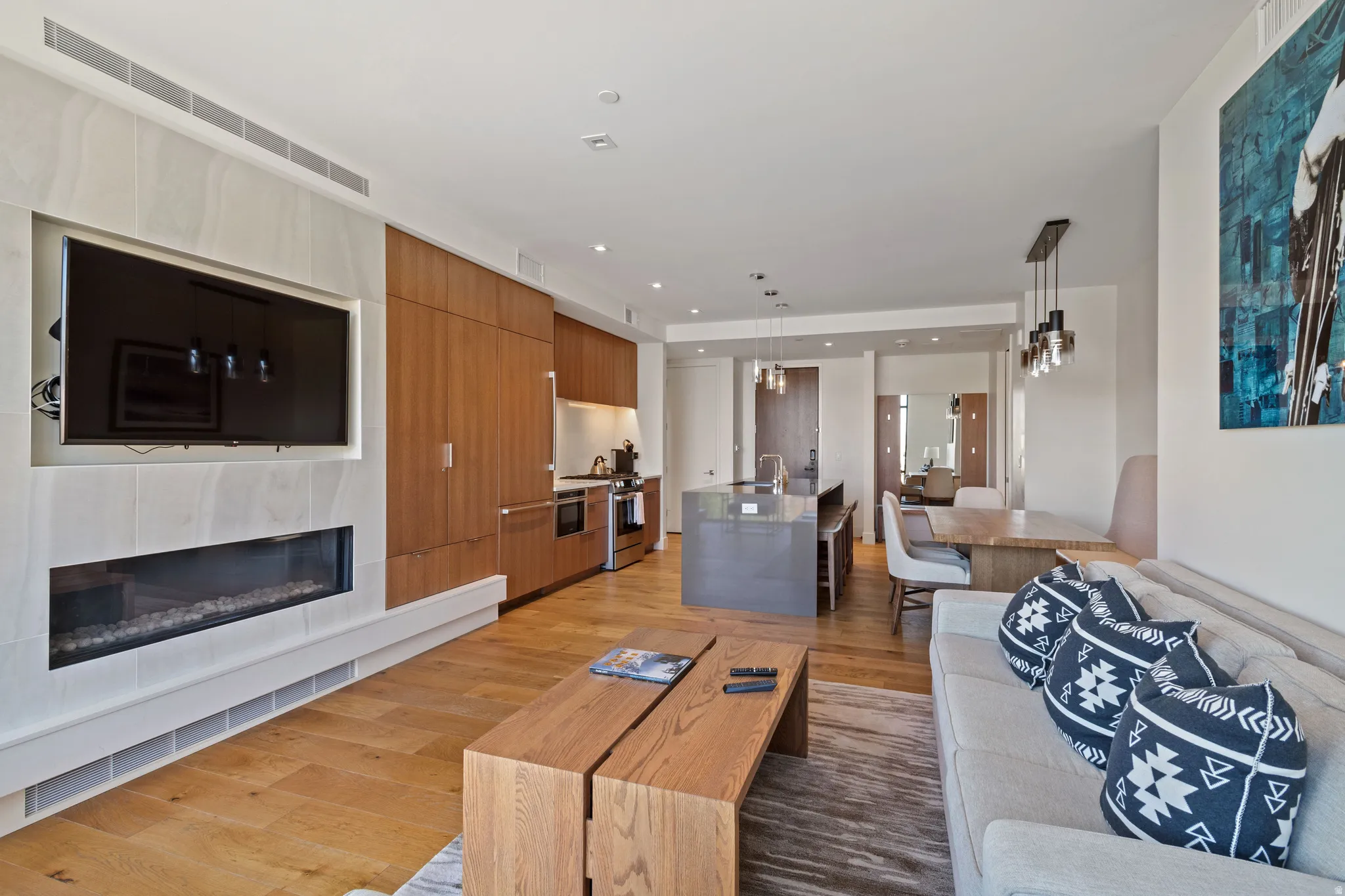 Living area featuring a glass covered fireplace, light wood-type flooring, and recessed lighting