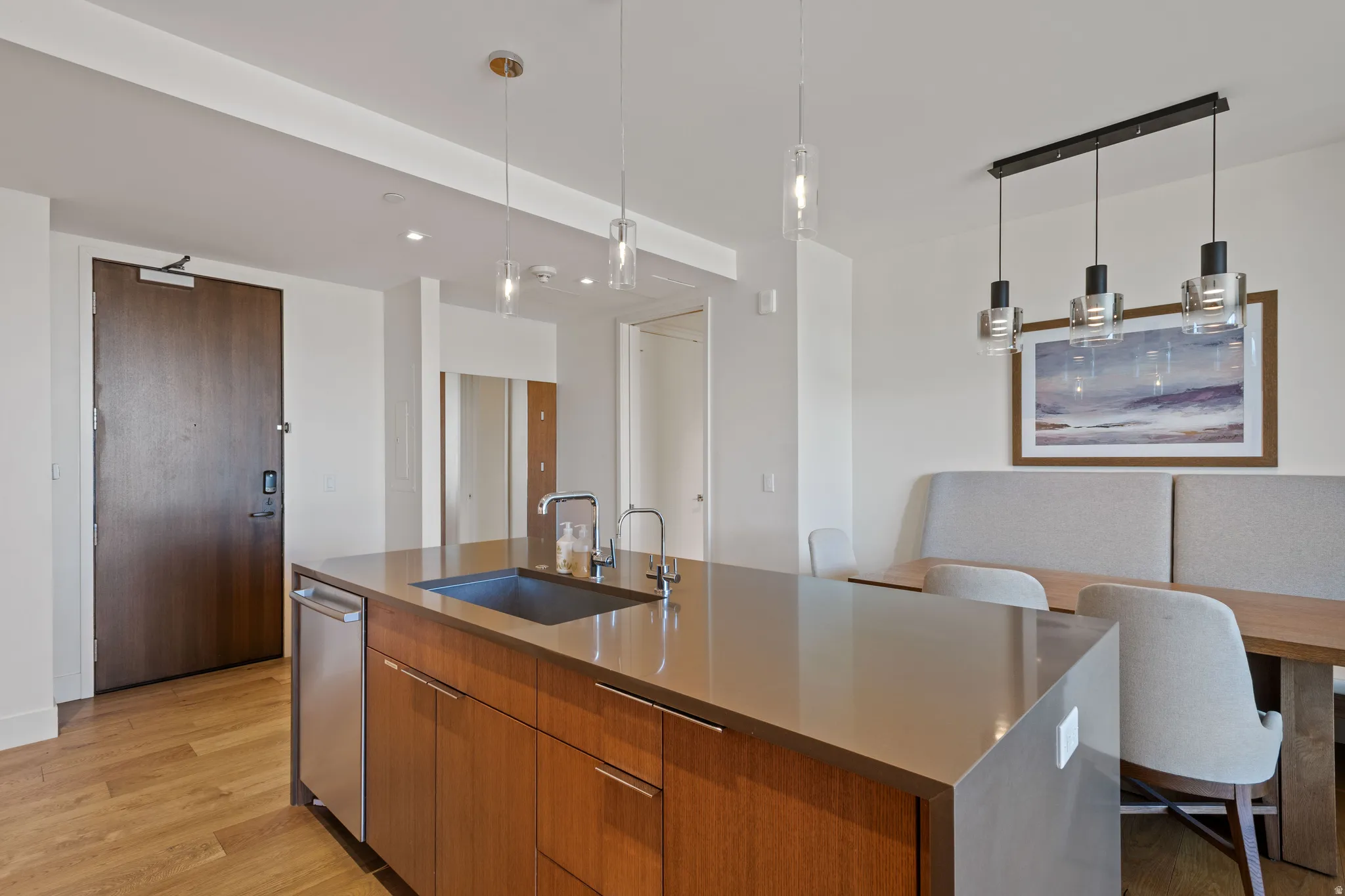 Kitchen with a kitchen island with sink, wood finish cabinets, modern cabinets, and dark stone countertops