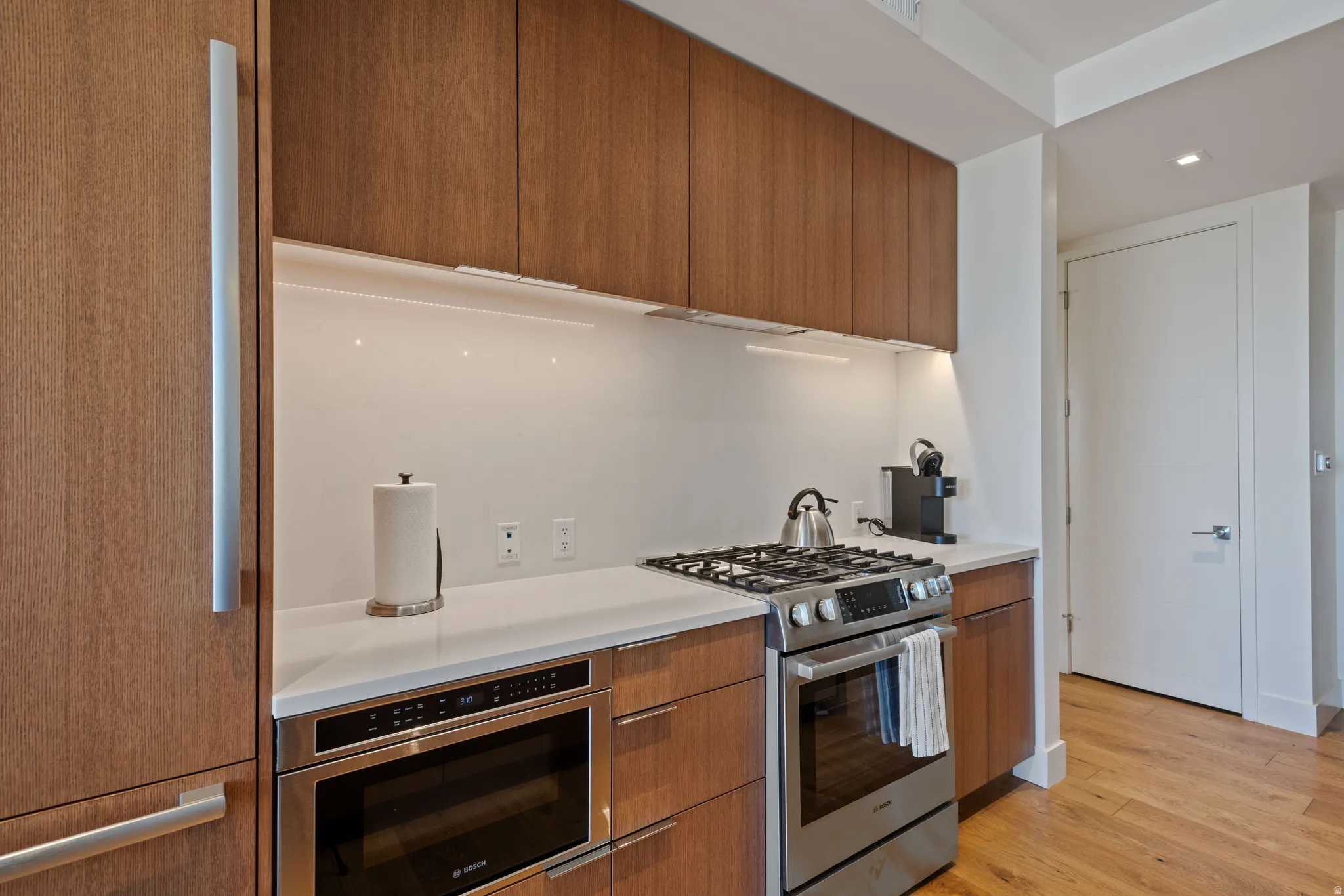 Kitchen with modern cabinets, stainless steel range with gas cooktop, wood finish cabinets, light wood-type flooring, and recessed lighting