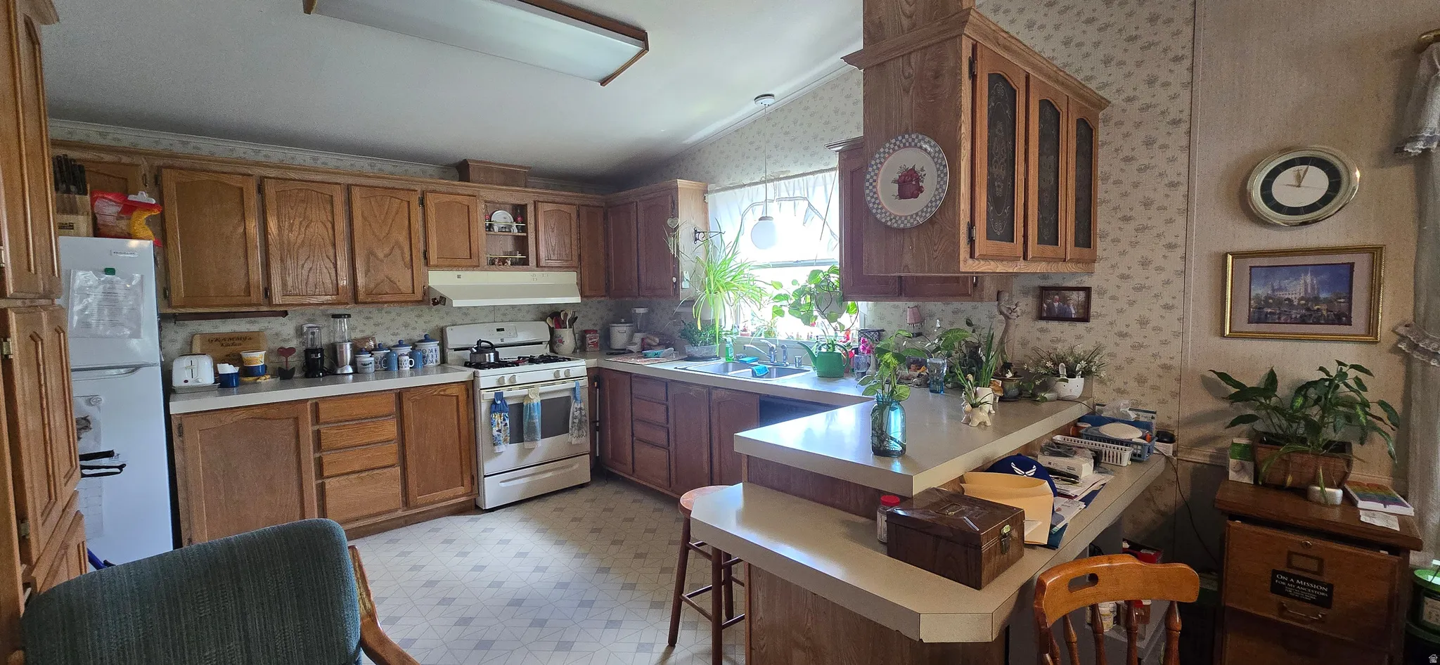 Kitchen with light floors, light countertops, white appliances, wood finish cabinetry, and wallpapered walls