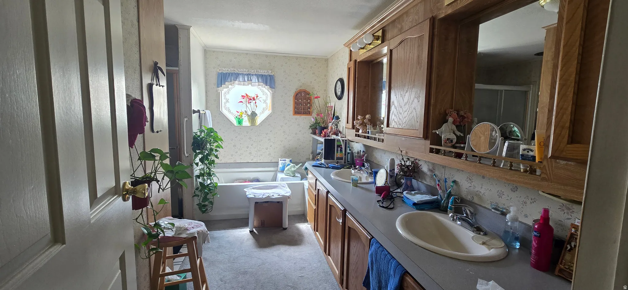 Bathroom with a garden tub, double vanity, wallpapered walls, and light colored carpet