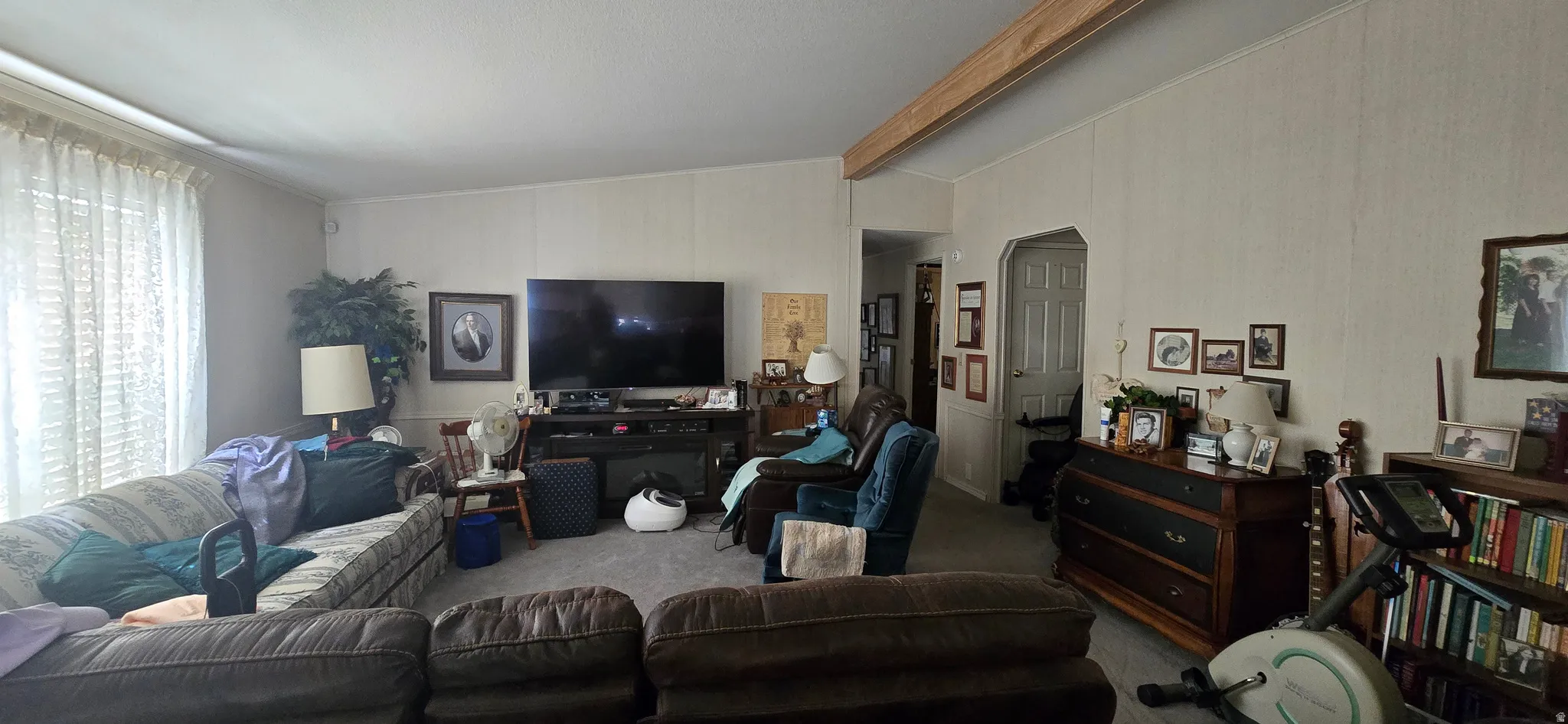 Living area with lofted ceiling with beams and carpet flooring