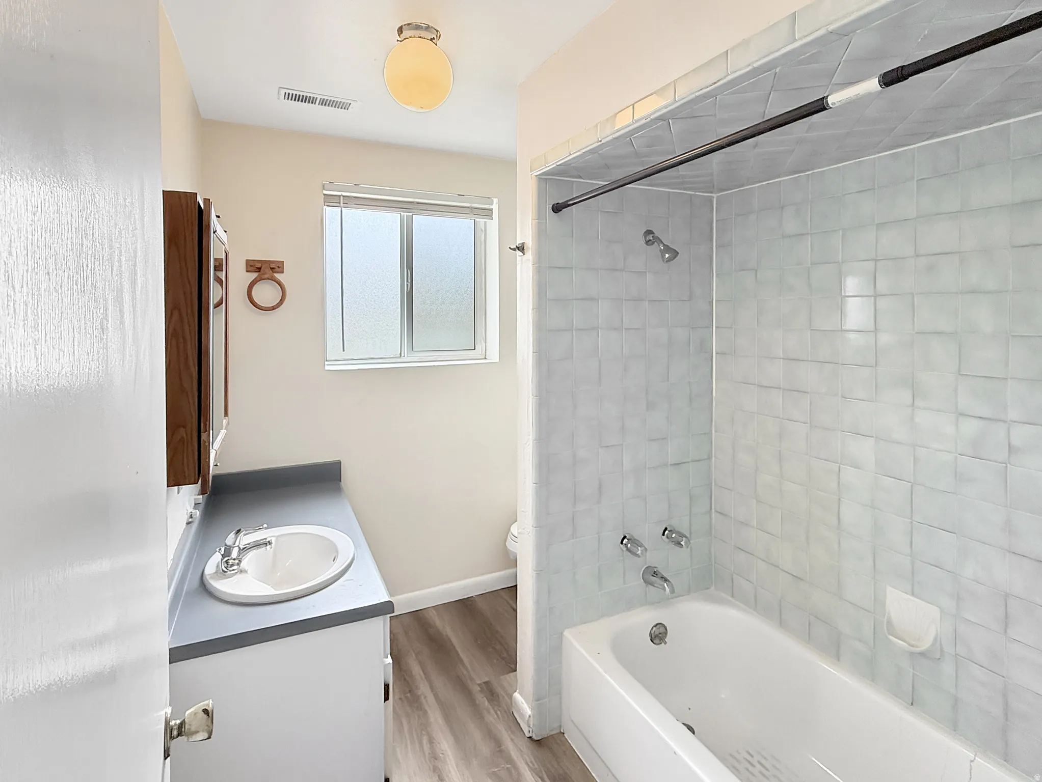 Bathroom featuring vanity,  shower combination, and light wood-style floors