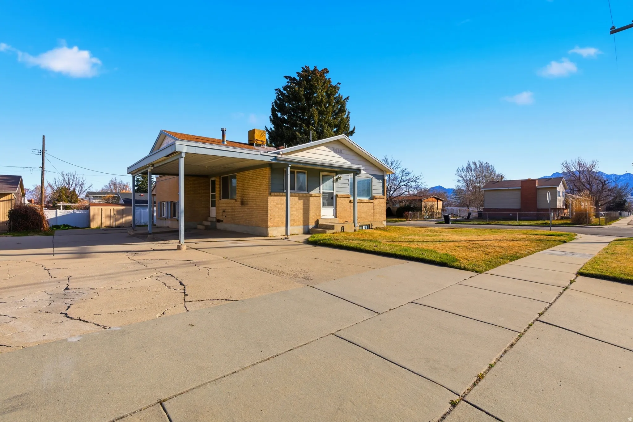 View of front of house with driveway, brick siding, and a carport