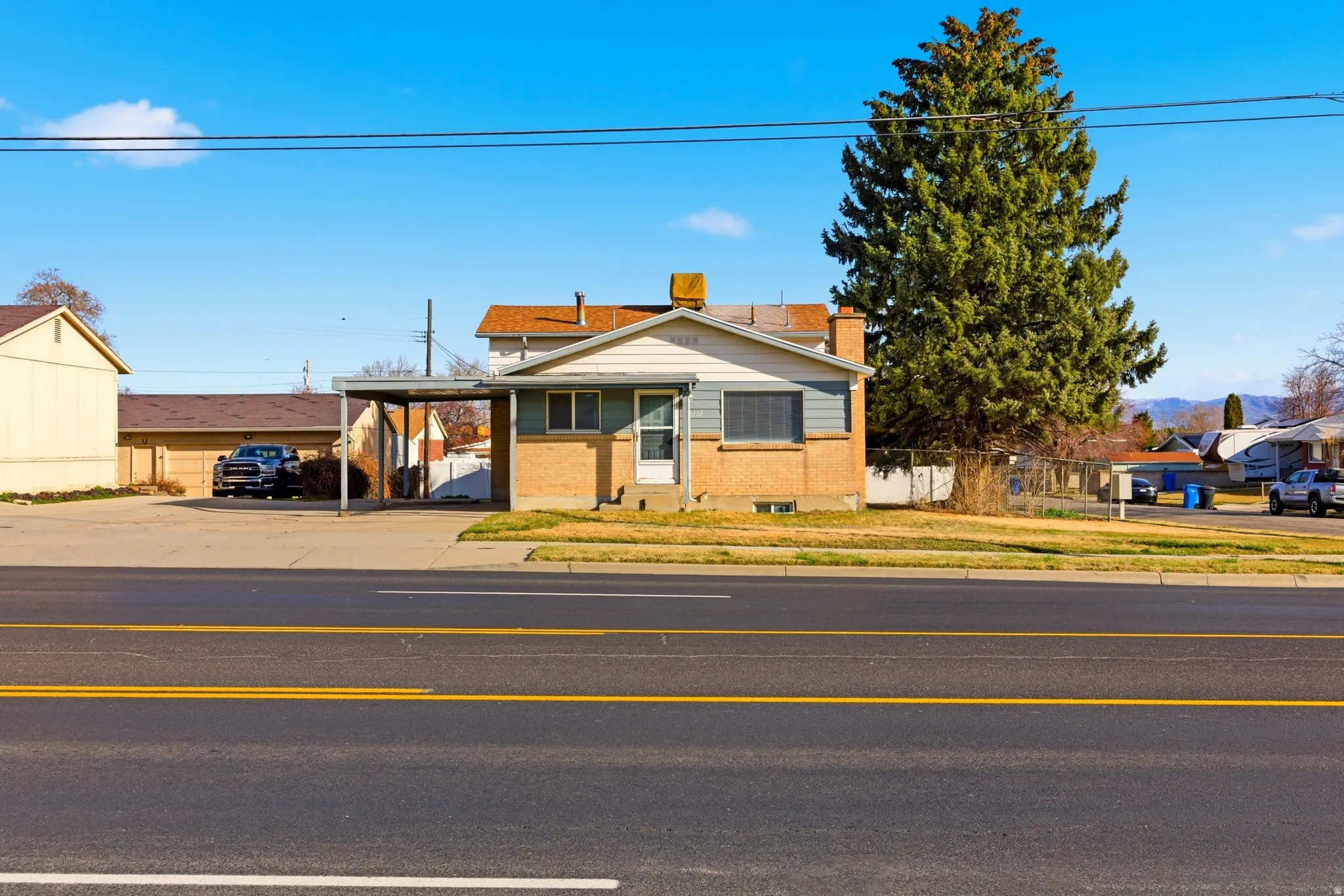 Multi-level with a carport, a chimney, brick siding, and driveway