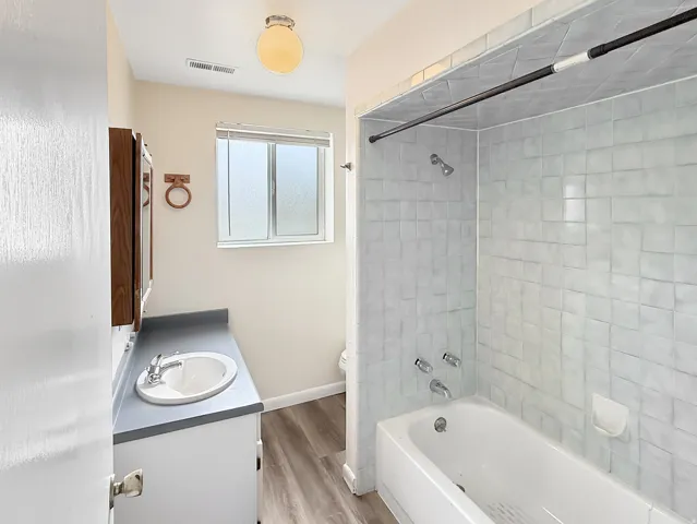 Bathroom featuring vanity,  shower combination, and light wood-style floors