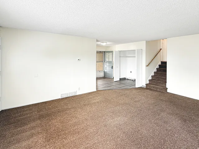 Unfurnished living room with a textured ceiling and dark carpet