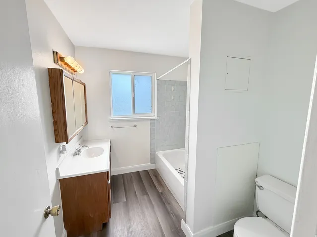 Bathroom with dark wood finished floors, vanity, and  shower combination