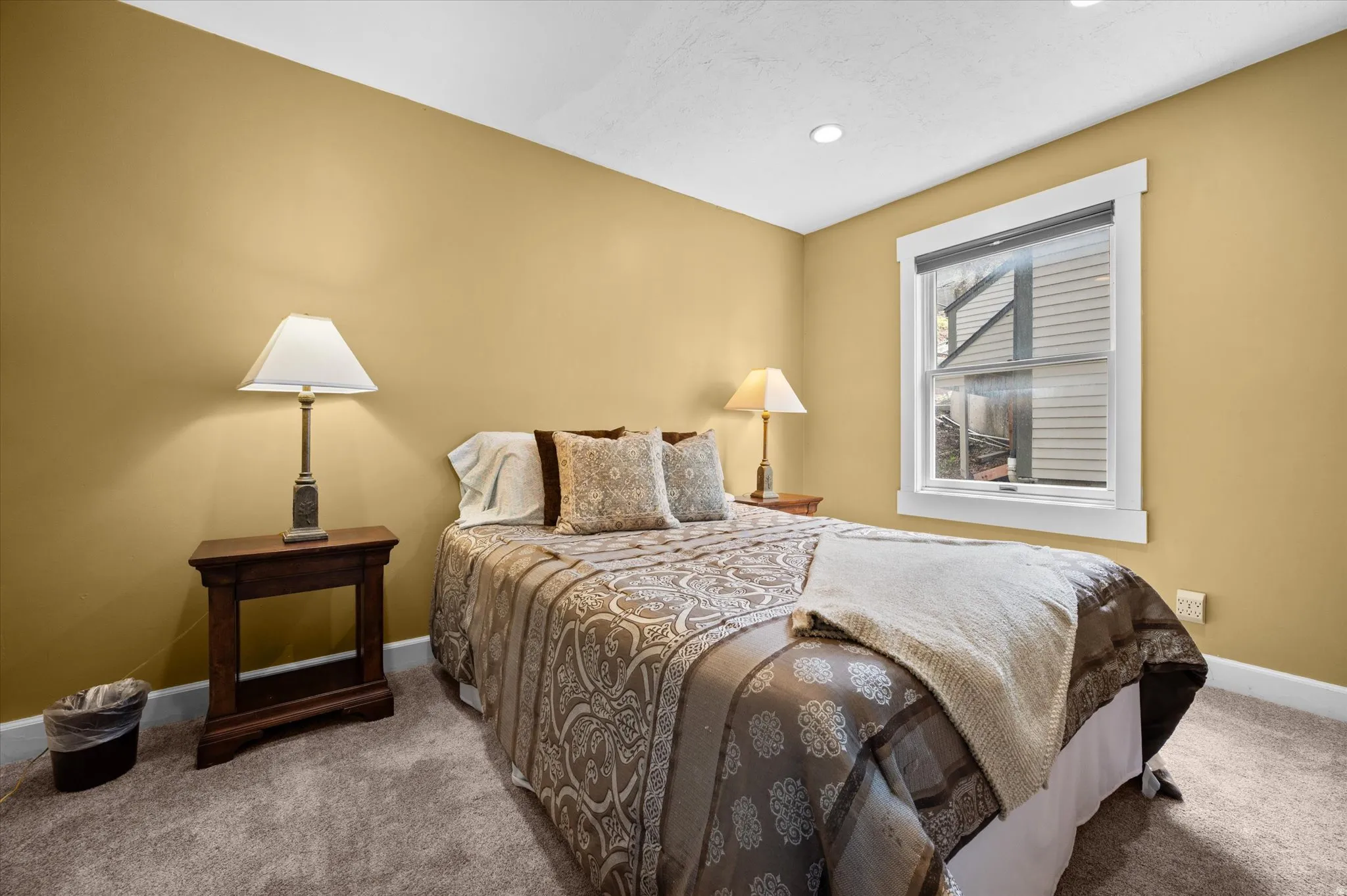 Additional guest bedroom with queen bed, storm window, and open closet with dresser.