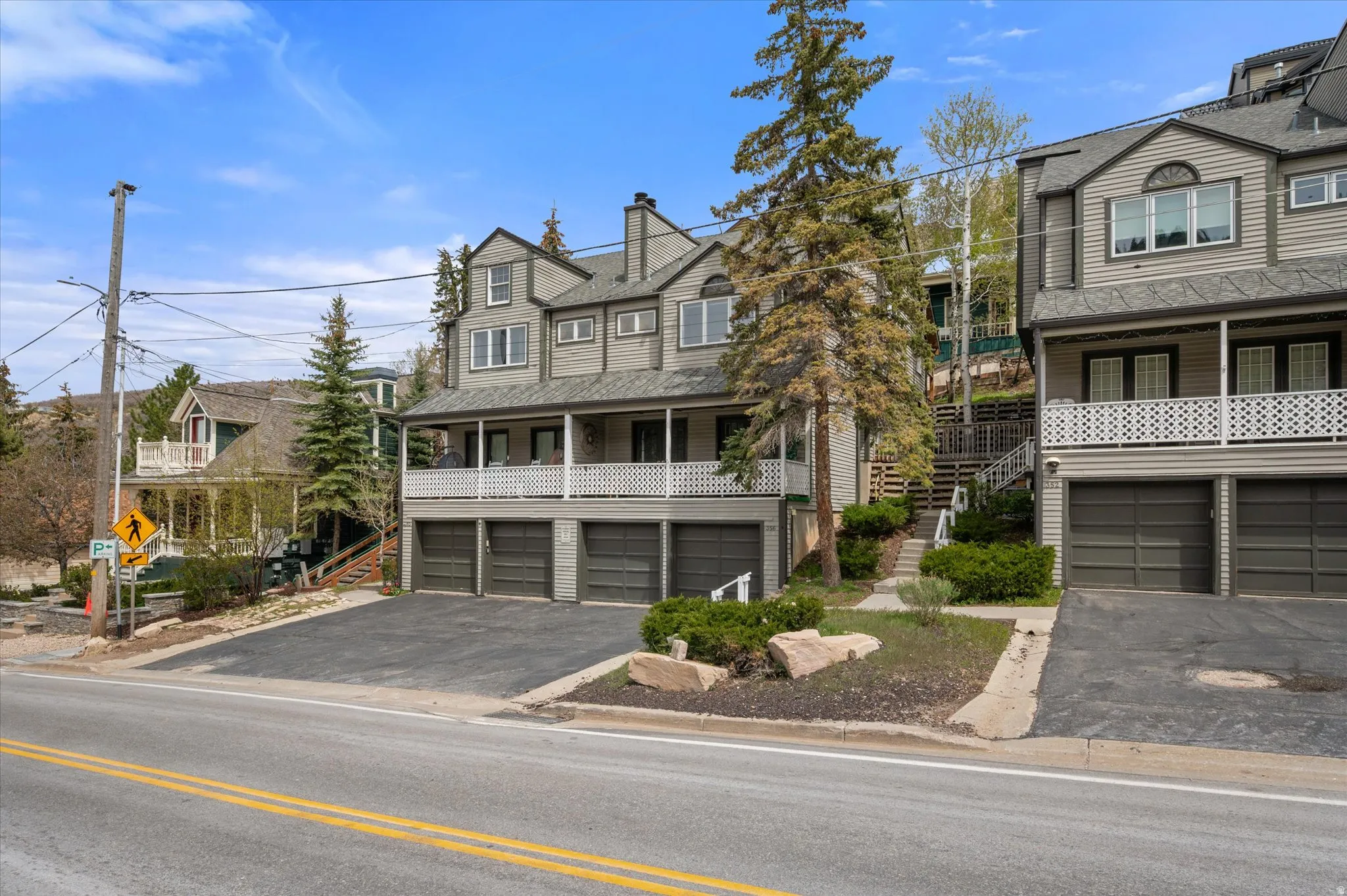 View of front of home landscaped with pines and foliage.