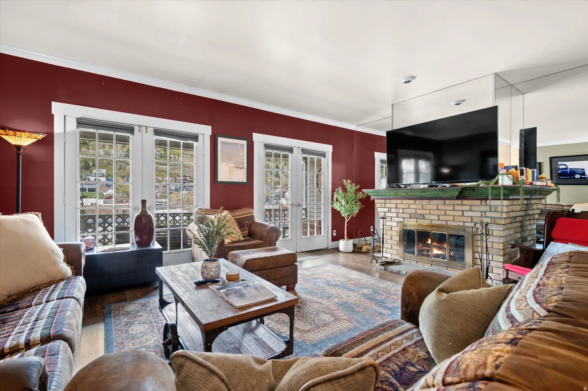 Spacious family room featuring french doors, LVP flooring, crown molding, and wood fireplace.