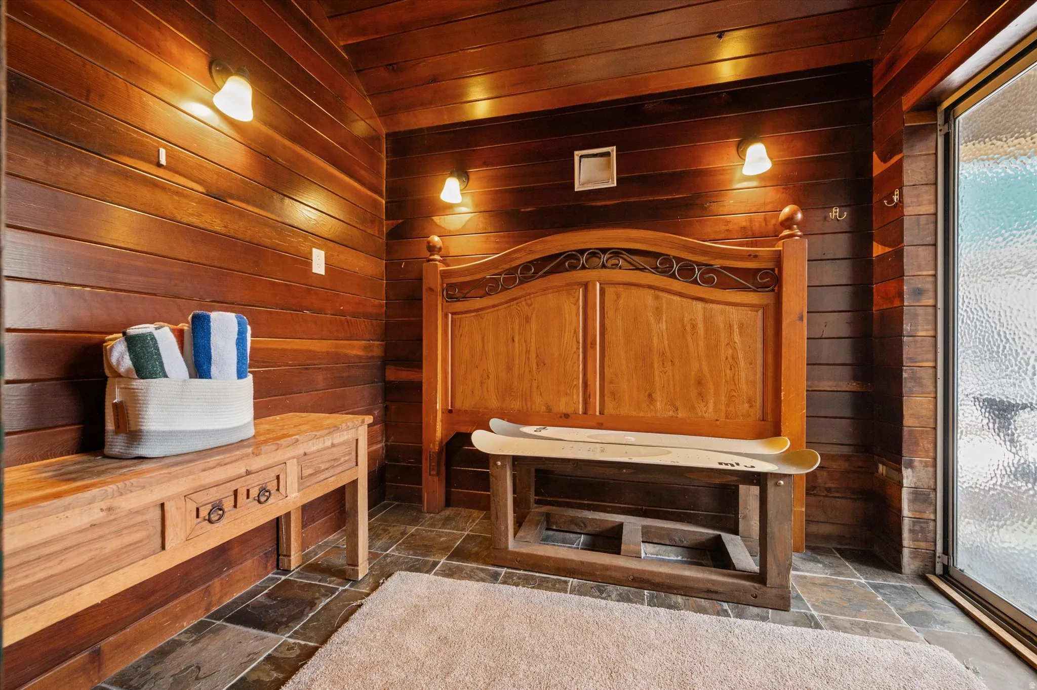 Interior space plumbed  for a sauna,  with solid wood walls, and slate flooring.