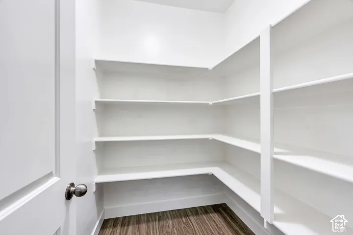White finished shelving, wood-finish flooring, and a white paneled door