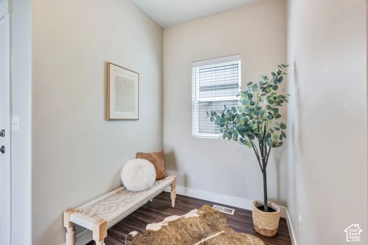 Wood-finish flooring with white baseboards and a single window with blinds