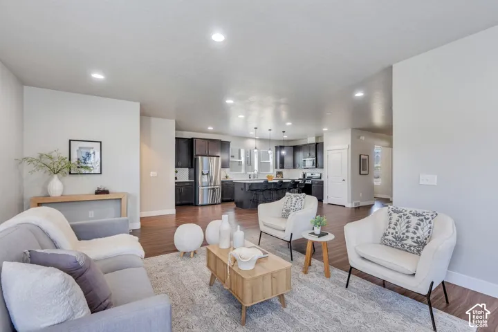 Recessed lighting throughout, wood-finish flooring, dark wood cabinetry, stainless steel appliances, and a kitchen island with pendant lighting