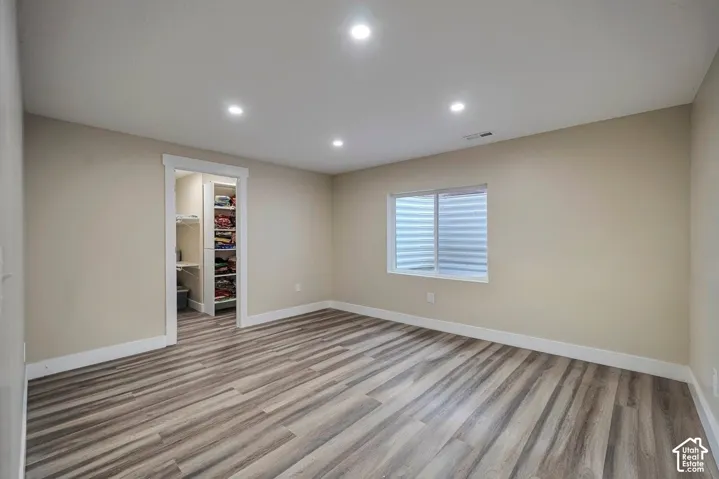 Spacious room featuring wood-finish flooring, recessed lighting, and a built-in closet with shelving