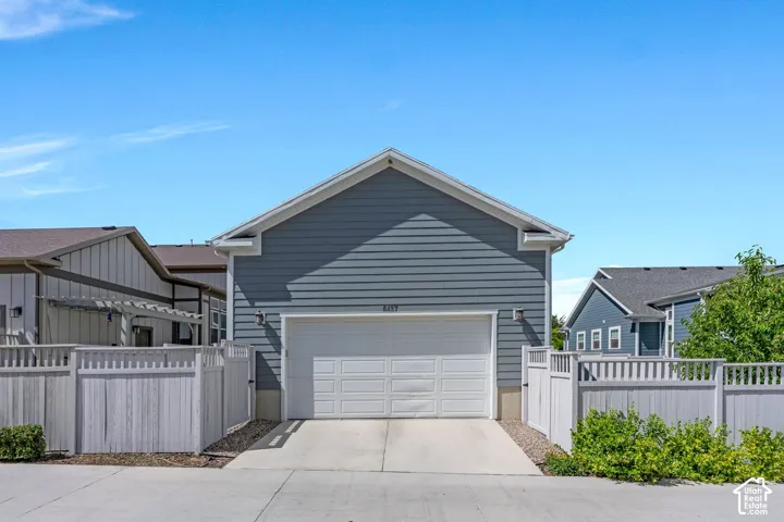 Attached garage with a white panel door, light grey siding, and a gabled roof