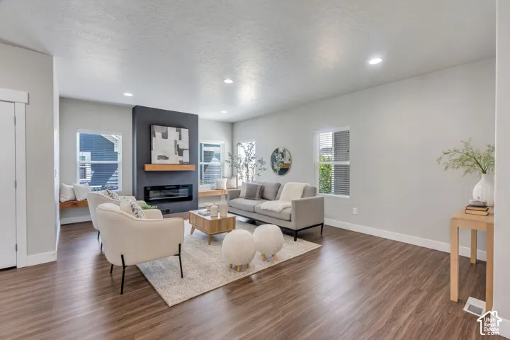 Recessed lighting, wood-finish flooring, a built-in fireplace with a dark surround, a wood mantle, and multiple windows with blinds