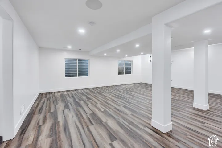Spacious room featuring recessed lighting, wood-finish flooring, white walls, and two window wells