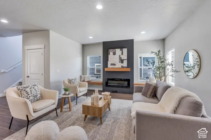 Spacious living area featuring wood-finish flooring, recessed lighting, and a contemporary linear fireplace with a wood mantle