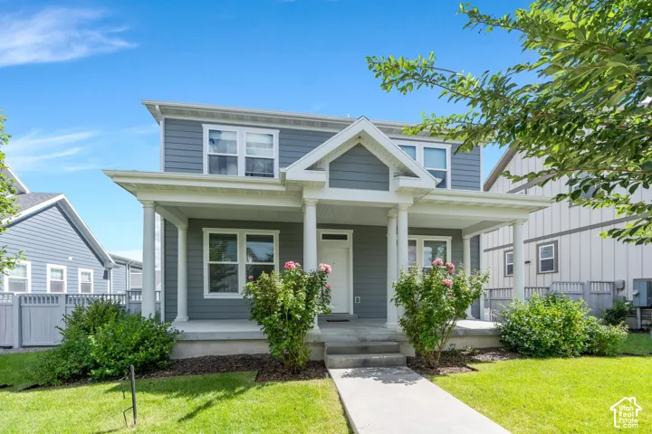Two-story exterior with gray siding, a covered front porch supported by columns, and a concrete pathway