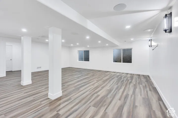 Expansive open space with wood-finish flooring, recessed lighting, and white walls