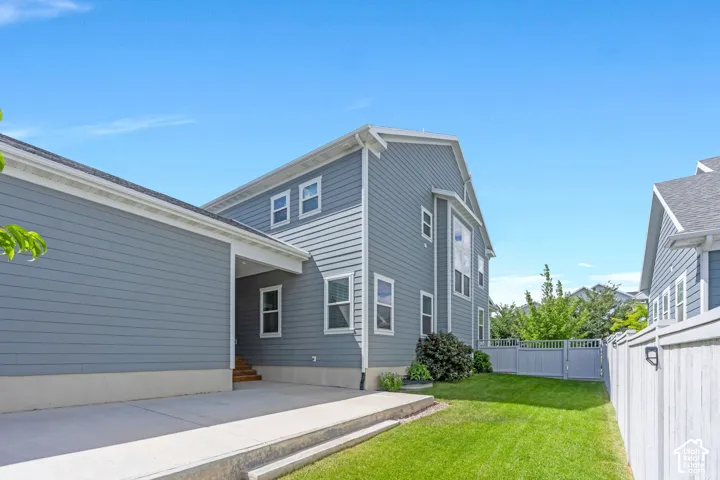 Blue siding exterior with white window frames, concrete driveway, and a manicured lawn