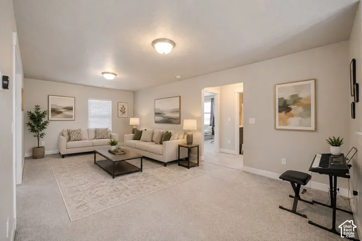 Recessed lighting and a neutral color palette enhance this open-concept living area with carpet flooring